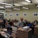 Opis wygenerowany automatycznie: Sala wykładowa wypełniona słuchaczami. Widzimy osoby skupione na prelekcji, słuchające uważnie. Atmosfera jest spokojna i skupiona na przekazie.