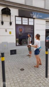 Para ludzi, mężczyzna i kobieta, stoi na chodniku, wpatrując się w witrynę sklepu optycznego.